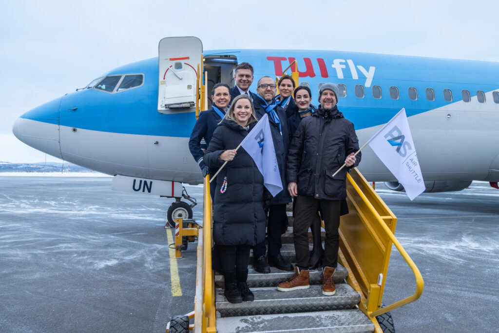 Eine Gruppe von Menschen steht auf einer Treppe vor einem TUIfly Flugzeug in Arvidsjaur und lächelt in die Kamera.