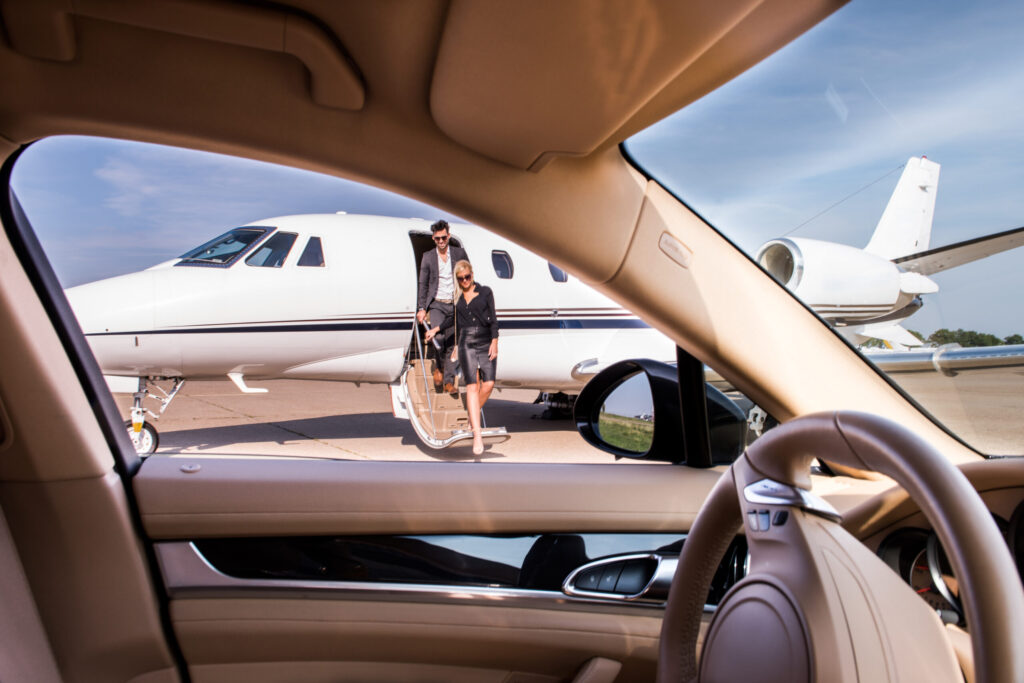 Geschäftsleute steigen aus einem Privatjet aus und laufen zum Auto.