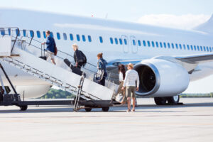 Außenaufnahme von Passagieren, die an Bord eines Flugzeugs gehen und die Treppe zum Flugzeug hinaufsteigen. Passengers boarding an aircraft via stairs – private charter flights and seamless group travel solutions by PASflights.