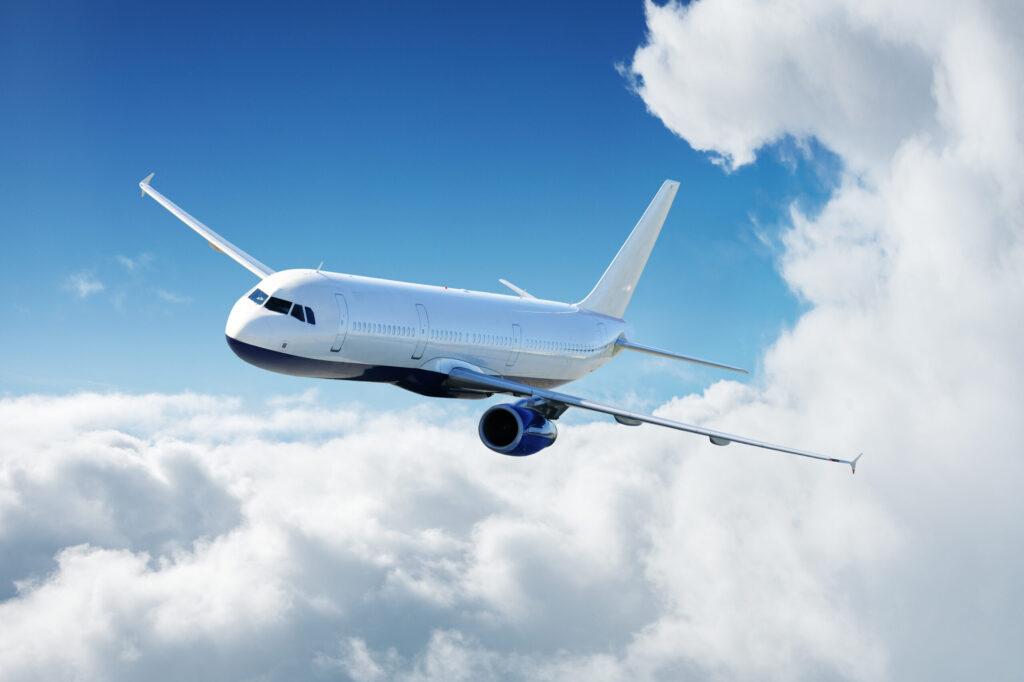 Flugzeug am Himmel fliegt an sonnigem Tag über den Wolken